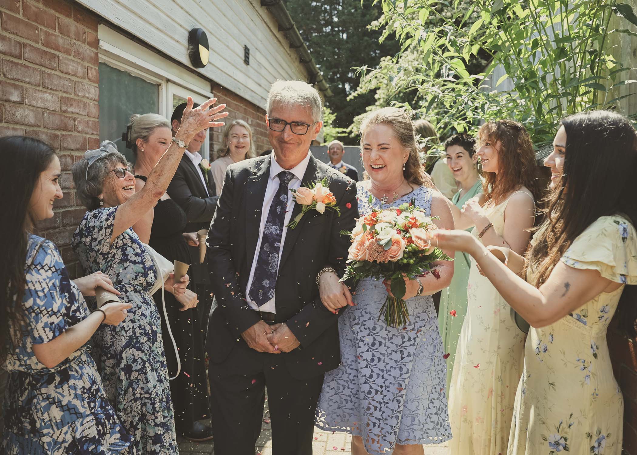 A bride and groom walking through a small aisle of confetti outside woodbridge registry office on a wedding day in Woodbridge captured by Suffolk Wedding Photographer Hayley Denston Photography